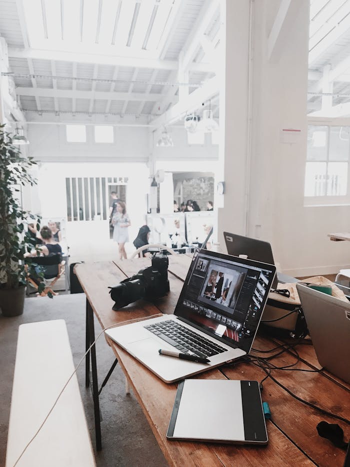 pexels photo 699459 A bright, modern workspace featuring laptops, a camera, and a drawing tablet in an indoor office.