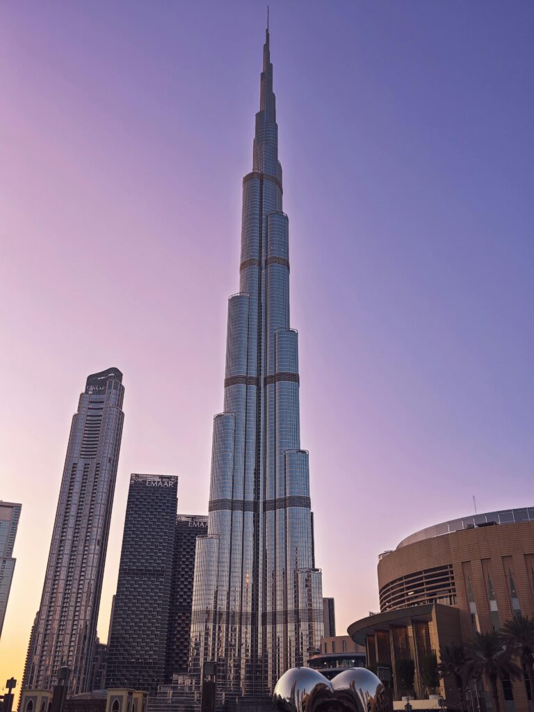 Stunning sunset view of Burj Khalifa in Dubai with surrounding skyscrapers and pink sky.